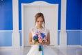 The bride admires her bouquet of flowers. The model in the wedding dress is in a large blue hall. The girl is holding in Royalty Free Stock Photo