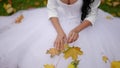 bride in autumn, beautiful woman in wedding dress is sitting on ground in park in fall day Royalty Free Stock Photo