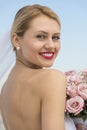 Bride In Backless Dress With Flower Bouquet Against Clear Sky