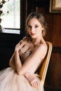 Bride in a beautiful dress sits on a chair in an old building. Lake Como