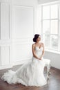 Bride in beautiful dress sitting on chair indoors