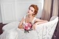 Bride in beautiful dress sitting resting on sofa indoors