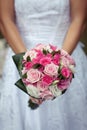 Bride in beautiful white dress is holding colorful wedding bouquet of pink, white, and purple roses Royalty Free Stock Photo