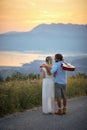 Bride in bohemian style dress, groom in casual clothes and guitar. Couple in love and hugging. Rear view. Nature, wedding, love Royalty Free Stock Photo