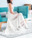 Bride in a bohemian white wedding dress sitting in a blue chair