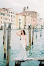 Bride with a bouquet stands on a wooden bridge against the backdrop of old houses in Venice Royalty Free Stock Photo