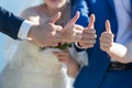 Bride, bridesmaid, groom and groomsman showing thumb up outdoors