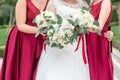 Bride and bridesmaid are holding bouquets of flowers in hands. Bridesmaid are on background. Bride is holding a wedding bouquet. Royalty Free Stock Photo