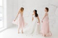 Bride and bridesmaids dancing in white studio with flying petals. Full-lenght portrait Royalty Free Stock Photo