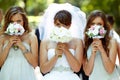 Bride and bridesmaids hide their faces behind little wedding bouqeuts