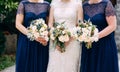 Bride and bridesmaids in identical blue dresses are standing side by side and holding bouquets in their hands, close-up Royalty Free Stock Photo
