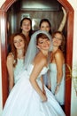 Bride and bridesmaids look funny while posing in an open door