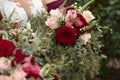 Bride with bridesmaids in magenta burgundy dresses with wedding florals - deep red and white roses with seeded eucalyptus leaves