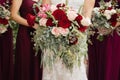 Bride with bridesmaids in magenta burgundy dresses with wedding florals - deep red and white roses with seeded eucalyptus leaves