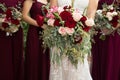 Bride with bridesmaids in magenta burgundy dresses with wedding florals - deep red and white roses with seeded eucalyptus leaves