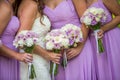 A bride and bridesmaids in purple dresses holding their bouquets