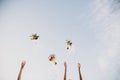 Bride and bridesmaids throwing wedding bouquets up in the sky in evening soft light. Stylish wedding bouquets with ribbons in sky Royalty Free Stock Photo