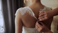 Bride buttoning wedding dress on the back