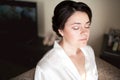 Bride with closed eyes showing bridal makeup in morning wearing white silk robe. Wedding preparation. Royalty Free Stock Photo