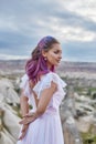 Bride with creative hair coloring looks into the distance in nature. Portrait of a woman with brightly colored hair standing in