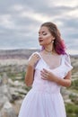 Bride with creative hair coloring looks into the distance in nature. Portrait of a woman with brightly colored hair standing in