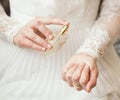 Bride in delicate elegant dress applying pefume on her wrist closeup