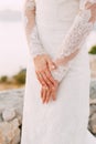 The bride in dress with lace sleeves folded her hands with a wedding ring on her finger, close-up Royalty Free Stock Photo