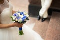 Bride in a dress standing in a green garden and holding a wedding bouquet of flowers and greenery. Royalty Free Stock Photo