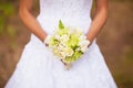 Bride in a dress standing in a green garden and holding a wedding bouquet of flowers and greenery and blur background Royalty Free Stock Photo