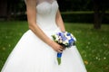 Bride in a dress standing in a green garden and holding a wedding bouquet of flowers and greenery-2 Royalty Free Stock Photo