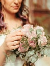 bride in a dress standing in a green garden and holding a wedding bouquet of flowers and greenery grain effect Royalty Free Stock Photo