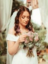 bride in a dress standing in a green garden and holding a wedding bouquet of flowers and greenery grain effect Royalty Free Stock Photo