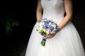 Bride in a dress standing in a green garden and holding a wedding bouquet of flowers and greenery. Royalty Free Stock Photo