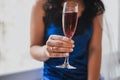 Bride dressed in blue satin suede pajamas holds a glass with red champagne
