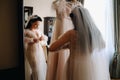 the bride, dressed in a boudoir transparent dress and underwear, stands at home in the morning by the mirror