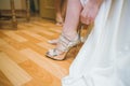 Bride dresses shoes before the wedding ceremony. Charges of the bride. Closeup detail of bride putting on high heeled