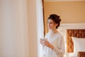 The bride is drinking coffee, bride holds a cup of coffee, bride in a white coat, morning of the bride, wedding day Royalty Free Stock Photo