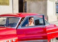 bride editorial photo shoot in a beautiful red vintage old timer car from the sixties in a city center