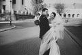Bride encloses a groom in her veil while he hugs her