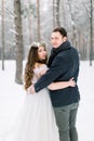 Bride in flower cotton wreath on the head and groom are hugging in the winter forest. Close-up. Winter wedding ceremony. Royalty Free Stock Photo