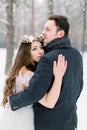 Bride in flower cotton wreath on the head and groom are hugging in the winter forest. Close-up. Winter wedding ceremony. Royalty Free Stock Photo