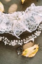 Bride garter, tiara on the head in hairstyle, wedding ring against the background of wooden texture and autumn leaves