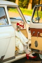 The bride gets out of the car in red shoes