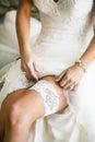 Bride lifting dress showing bridal garter before her wedding ceremony