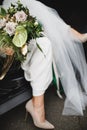 The bride is going out of the car with a big flover bouquet closeup