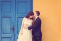 Bride and groom against yellow wall and blue door Royalty Free Stock Photo