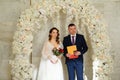 bride and groom in an arch of flowers at ceremony with a marriage certificate. Royalty Free Stock Photo