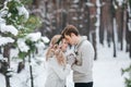 Bride and groom in beige knitted pullovers in snowy forest. Newlyweds is touching foreheads. Winter wedding