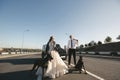Bride and groom, in black glasses and leather jackets with Dobermans near the car on the road