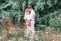 Bride and groom with a bouquet of peonies posing against the backdrop of the forest Royalty Free Stock Photo